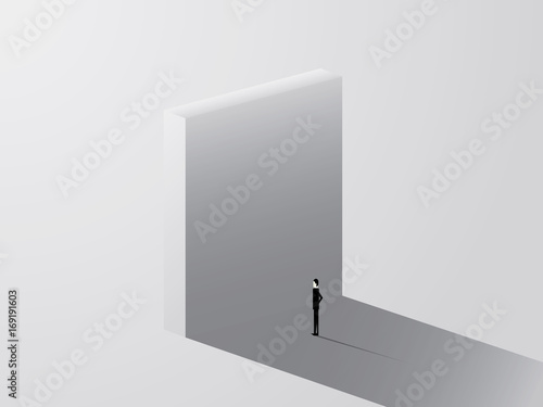 Businessman standing in front of huge wall as a symbol of business challenge and overcoming. Business challenge.