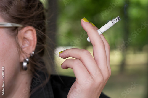 Woman smoking and holding a cigarette in a hand