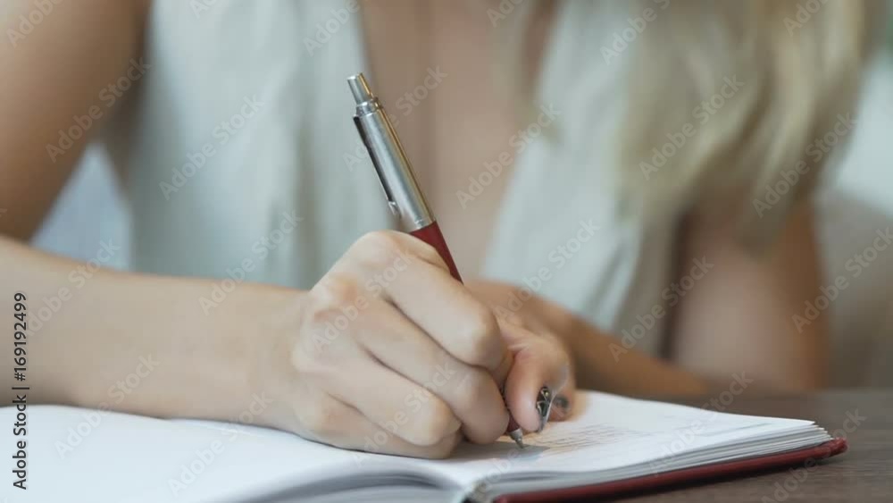 Close up of woman writing in journal Close up of woman writing in journal