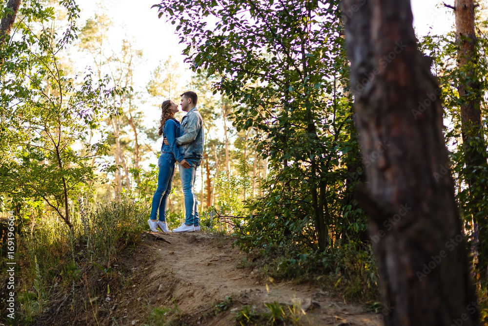 Fototapeta premium Full length side view of a romantic couple standing in forest