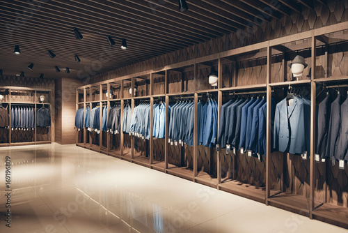 Interior of the business suit shop. Strict premium expensive suits hang in a row on hangers in large quantities