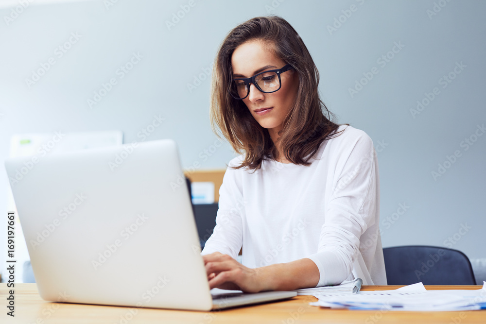 Potrait of very concetrated young startup businesswoman working hard on laptop in bright home office Potrait of very concetrated young startup businesswoman working hard on laptop in bright home office