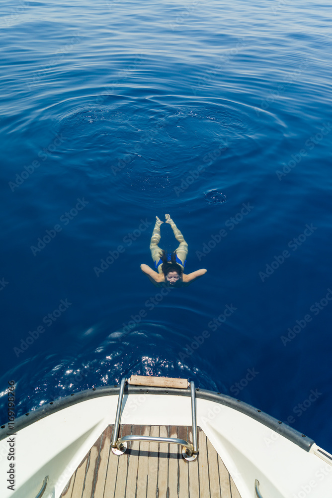 Fototapeta premium Young woman swimming by the sailing boat