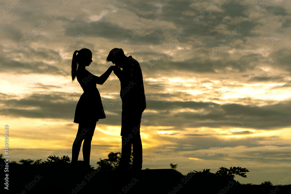 Silhouette couple in love Men ask for married and kissing at the hands of women on beautiful sunset background , valentine concept