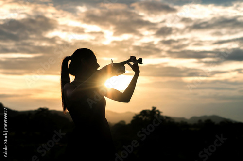 silhouette Violin woman player on sunset background