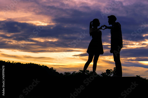 Wallpaper Mural Silhouette couple in love fingers a heart shape as a symbol of love on beautiful sunset background , valentine concept Torontodigital.ca