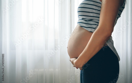 Unrecognizable pregnant woman holding her tummy in the bedroom Free Download Unrecognizable pregnant woman holding her tummy in the bedroom - GFXLoad