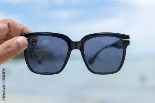 hand holding sunglasses on the beach