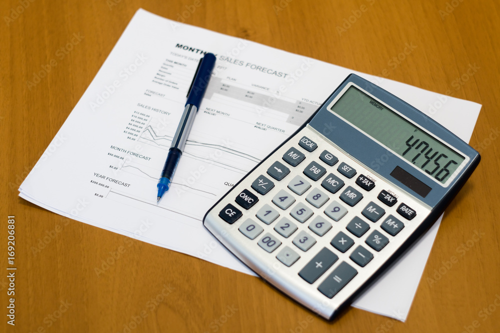 Finance, banking and business concept with charts, graphs, calculator and pen on wooden background