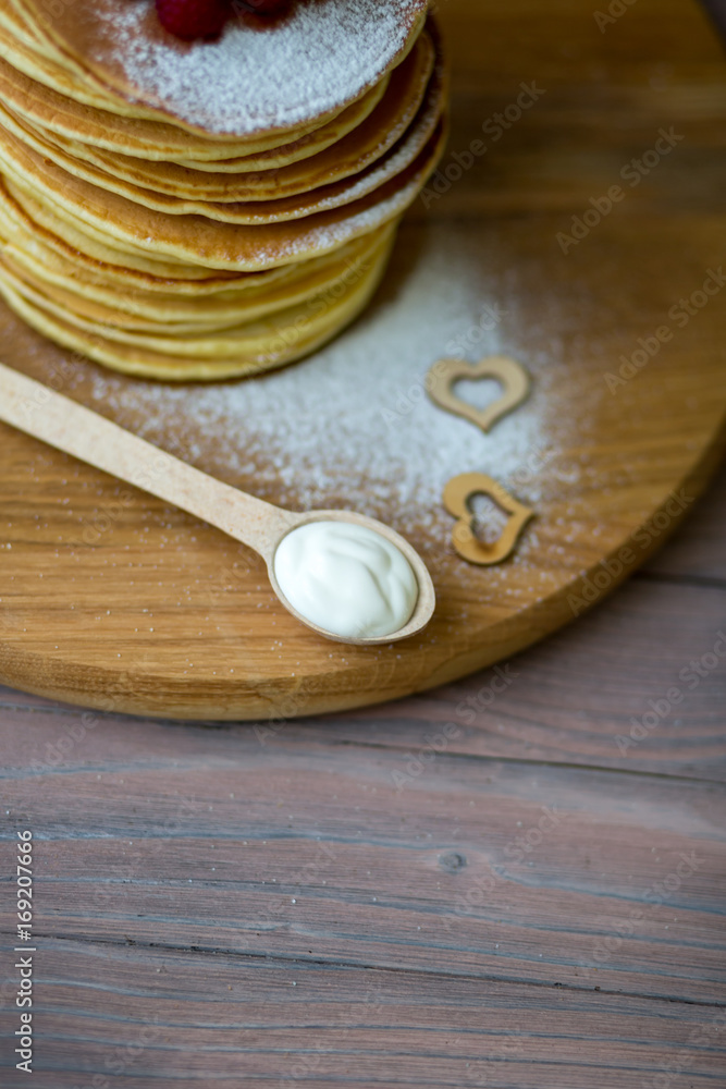 Tasty homemade pancakes with cream and raspberry. On wooden table. Village kitchen