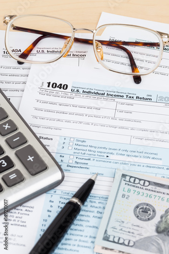 Tax form with calculator, pen, glasses, and dollar banknote