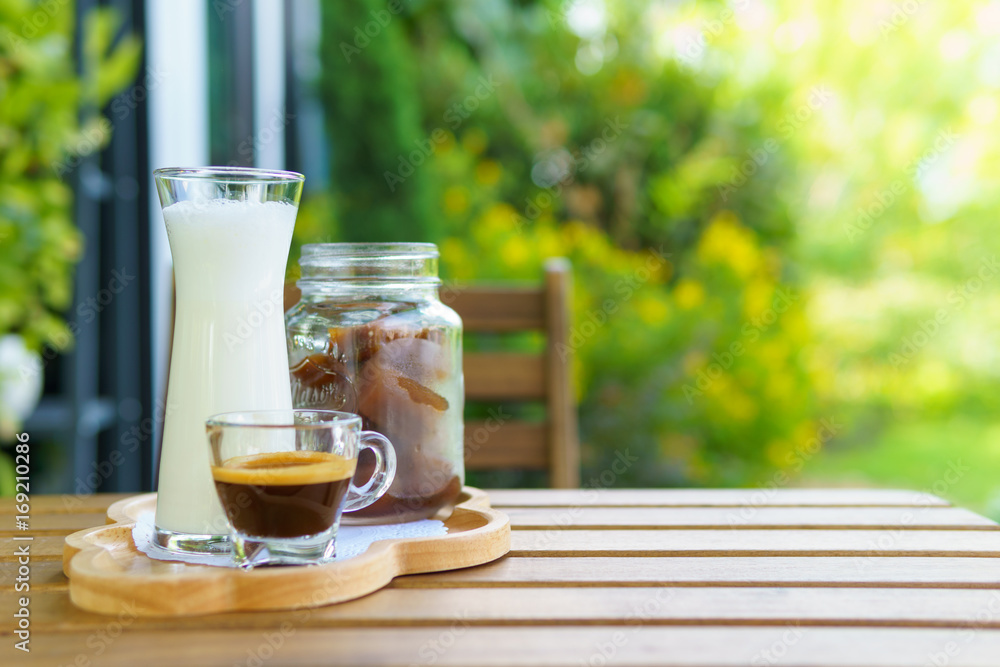 iced coffee cube latte with milk and shot of espresso on the wooden table in the garden. bright tone. with copy space for text iced coffee cube latte with milk and shot of espresso on the wooden table in the garden. bright tone. with copy space for text