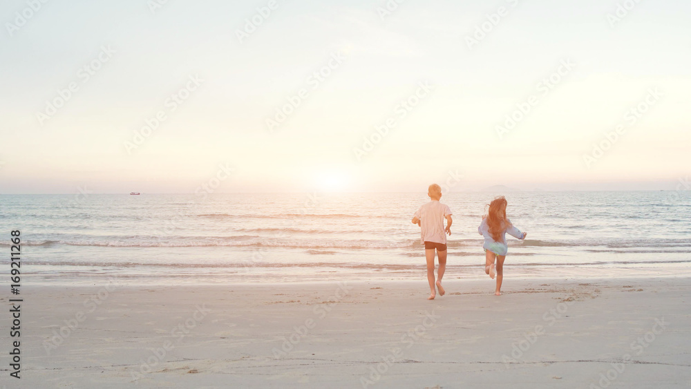 Little brother and sister running into the sea