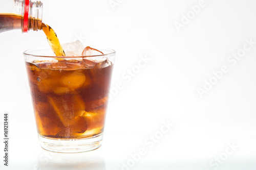 soft drink with caffeine is poured into a glass with ice on the background.