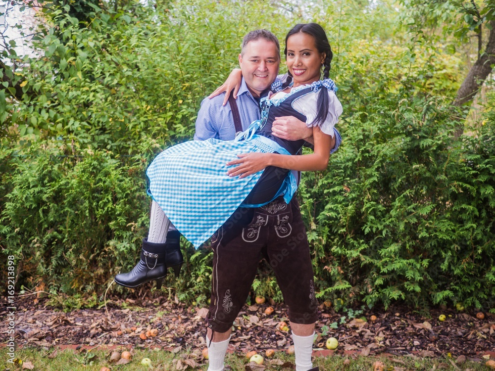 Fototapeta premium Oktoberfest - Couple in traditional bavarian clothes is standing under an apple tree