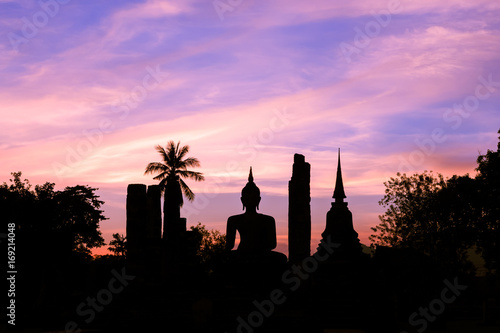 Buddha statue in Wat Maha That at sun set silhouette, Shukhothai Historical Park, Thailand photo