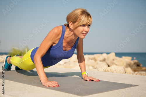Young athletic woman exercising outdoors: pushups for upper body strength
