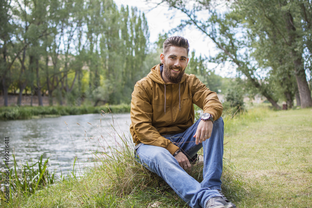 Obraz premium Man sitting on the bank of the river.
