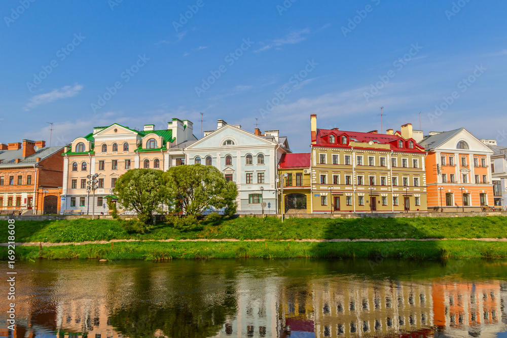 View of the old street by the river in the center of the city with reflection in the water. Pskov, Russia