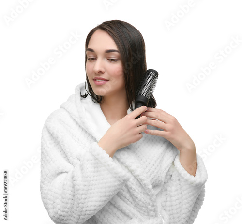 Beautiful young woman combing her hair after shower on white background