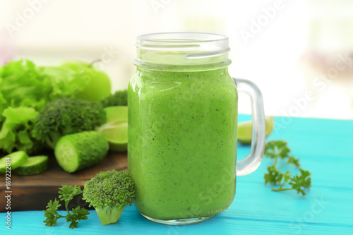 Mason jar with fresh green smoothie on table