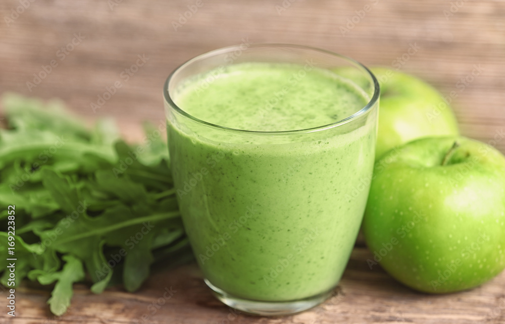 Glass of green smoothie, arugula and apples on wooden table Glass of green smoothie, arugula and apples on wooden table