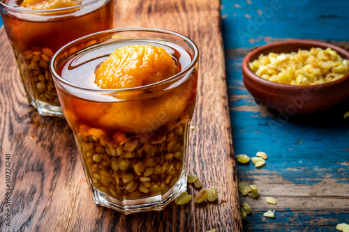 Mote con huesillo. Traditional Chilean drink made from cooked husked wheat and dried peach on wooden board, rustic blue background