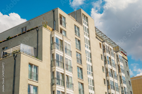 modern apartment building with yellow facade and fluffy clouds