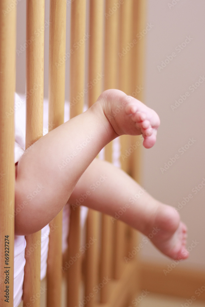 Pies de bebe saliendo entre los barrotes de una cuna Stock Photo | Adobe  Stock