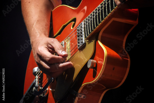 Man's hands playing on an electric guitar on stage, entertainment of a guitarist artist with his music instrument, close up