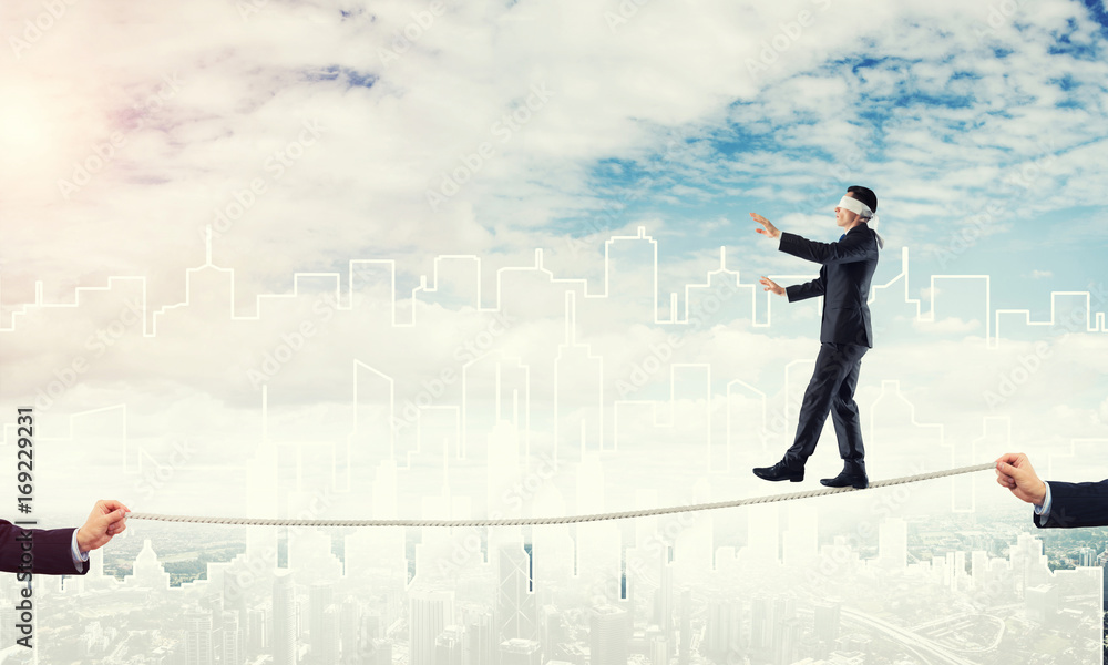Business concept of risk support and assistance with man balancing on rope Business concept of risk support and assistance with man balancing on rope