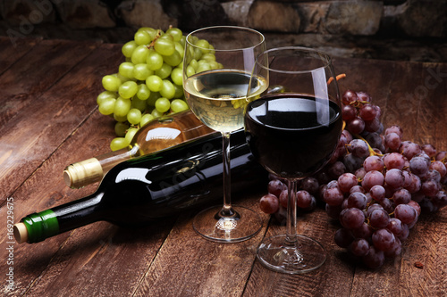Obraz na plátně Red Wine bottle and white wine with grapes and glasses on wooden background