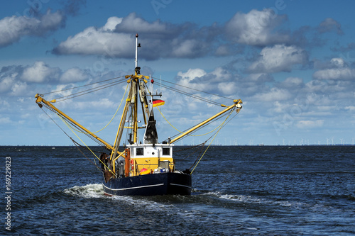 crabs or shrimp fishing boat on the North Sea under a blue sky with clouds, copy space