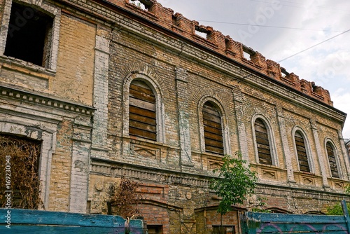 старый разрушенный дом из коричневого кирпича с заколоченными окнами