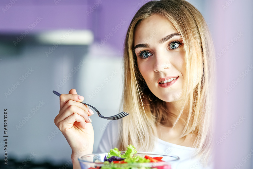 Young happy woman eating vegetable salad with a fork. The concept is healthy food, diet, vegetarianism, weight loss. Young happy woman eating vegetable salad with a fork. The concept is healthy food, diet, vegetarianism, weight loss.