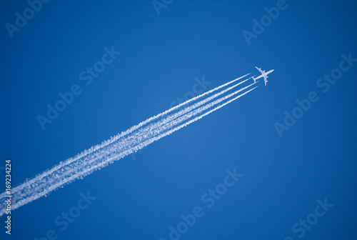 A jet plane flying overhead diagonally with condensation trail. © Mark