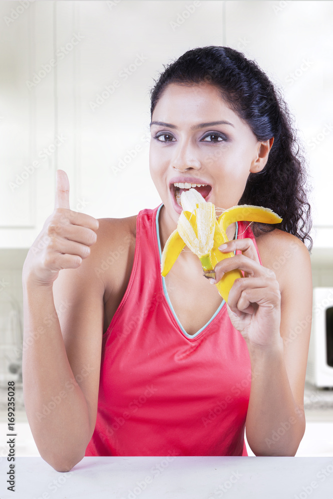Woman with banana and thumb up in kitchen Woman with banana and thumb up in kitchen