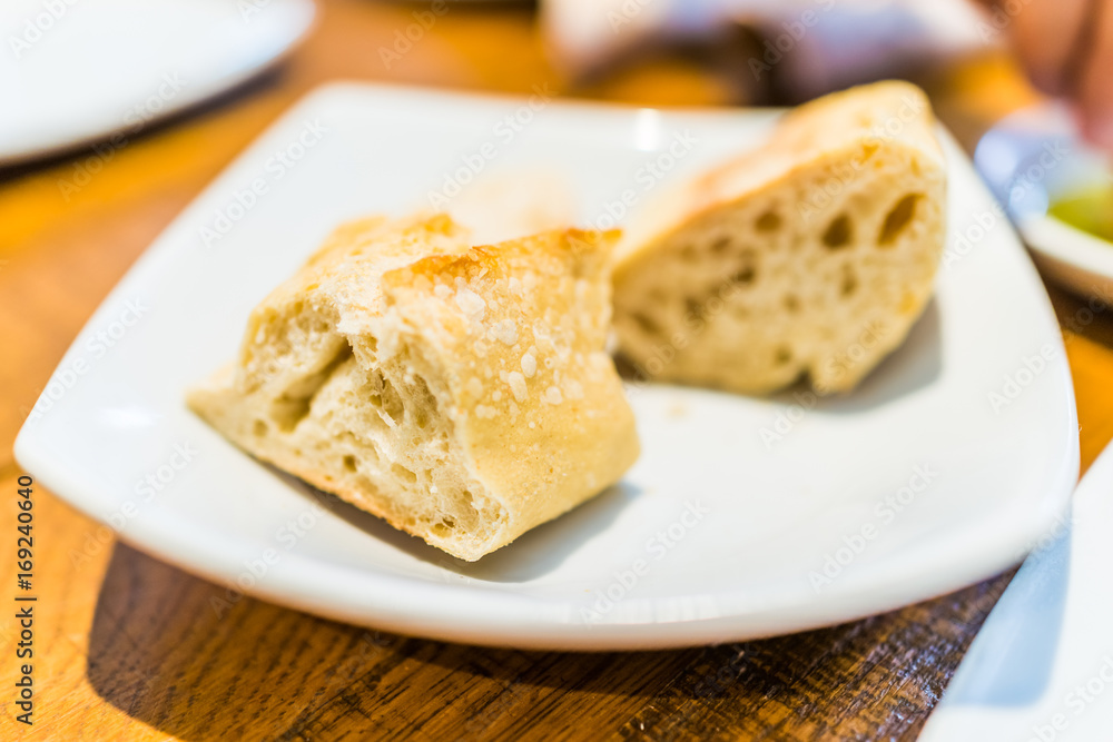 Macro closeup of fresh baguette bread slices on plate in restaurant table
