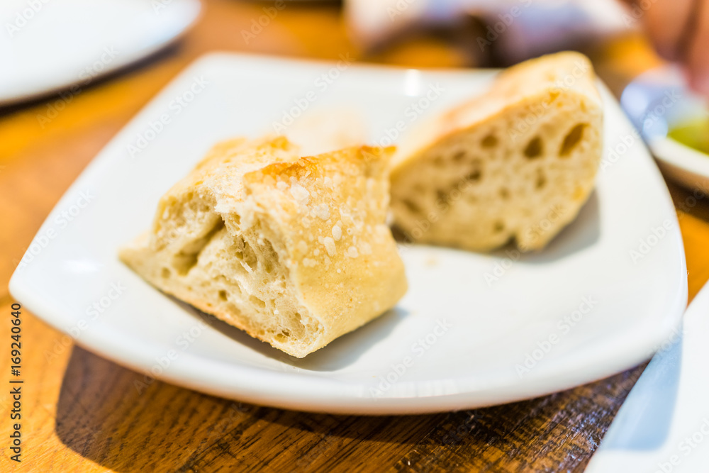 Macro closeup of fresh baguette bread slices on plate in restaurant table Macro closeup of fresh baguette bread slices on plate in restaurant table