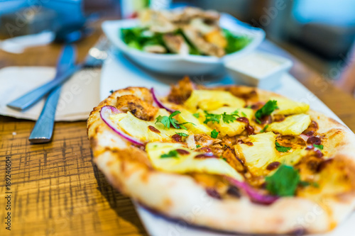 Macro closeup of small individual pineapple pizza on plate in restaurant