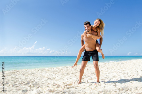 Fotografie Couple piggyback ride at the beach