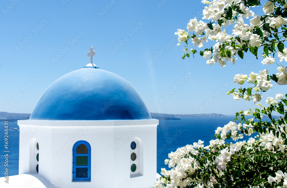 Greek church with white flowers overlooking ocean