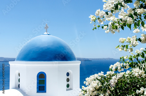 Greek church with white flowers overlooking ocean
