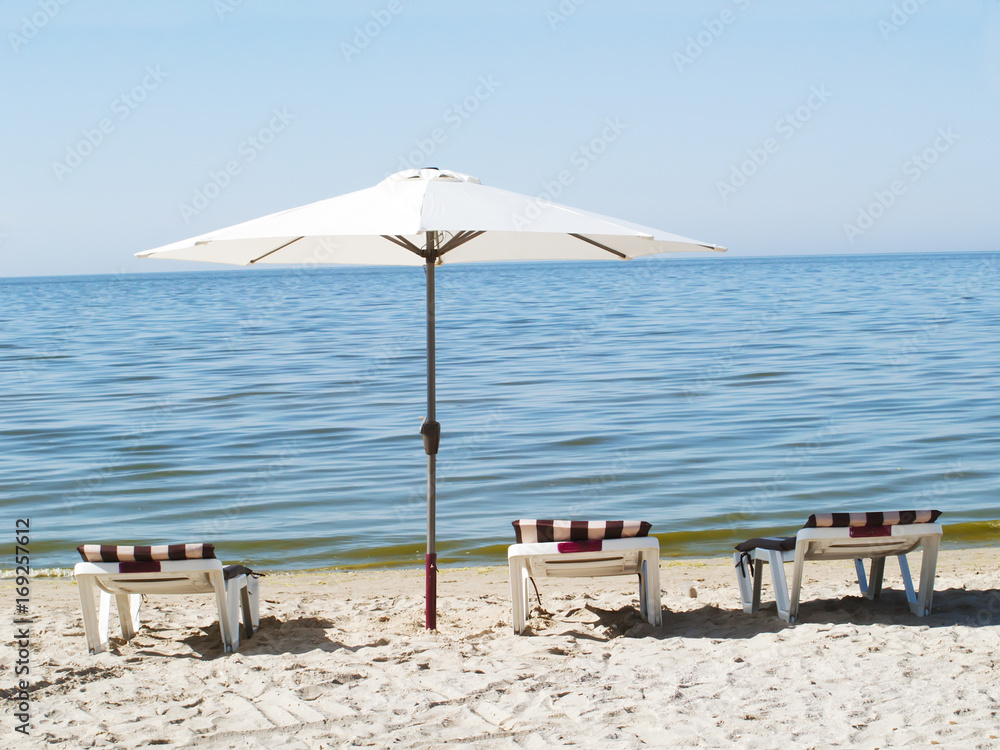 Three sun loungers and a beach umbrella on a deserted beach