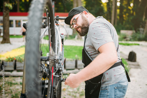 Repairman works with bike wheel, cycle workshop