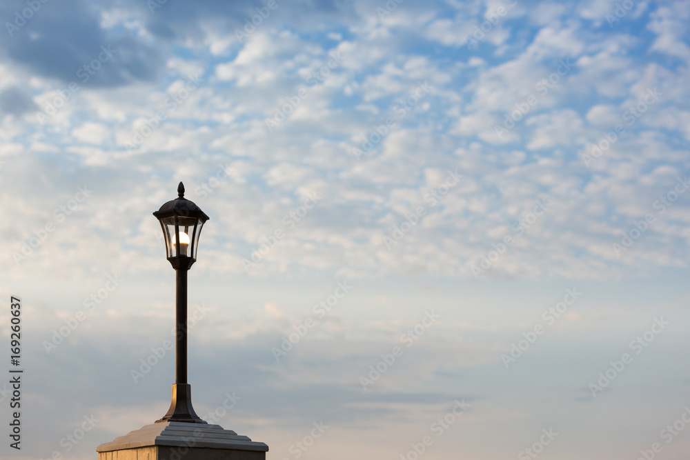 Lantern on an iron pillar against a cloudy sky background Lantern on an iron pillar against a cloudy sky background