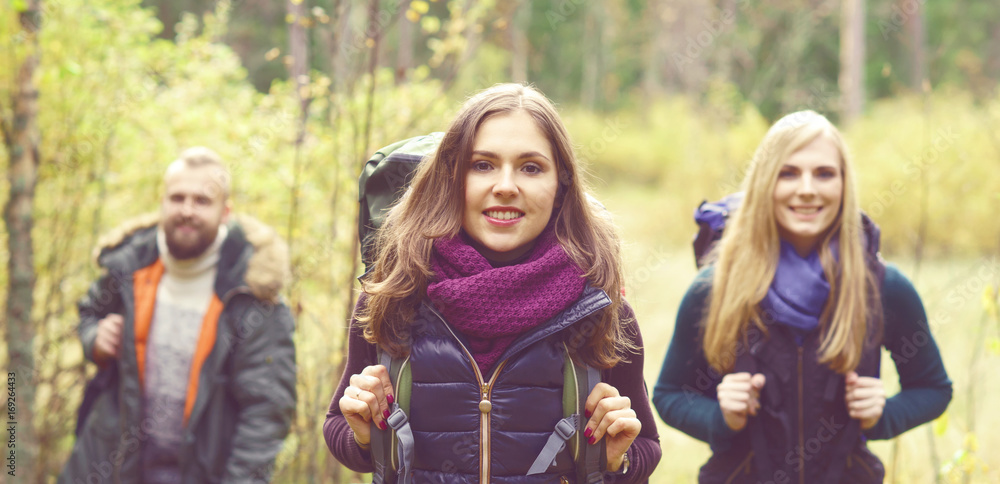 Young happy friends walking in forest and enjoying a good autumn day. Camp, tourism, hiking, trip, concept. Young happy friends walking in forest and enjoying a good autumn day. Camp, tourism, hiking, trip, concept.