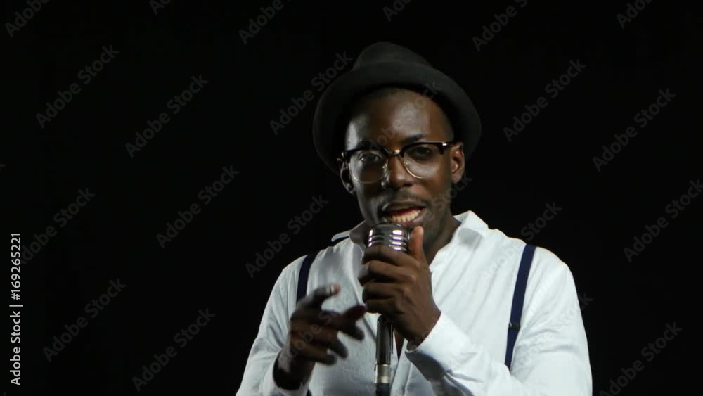 Man young african american approaching the microphone singing in a recording studio. Black background. Close up Man young african american approaching the microphone singing in a recording studio. Black background. Close up