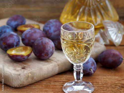 Photo Plum brandy Slivovtz in crystal glasses and plums on wooden background