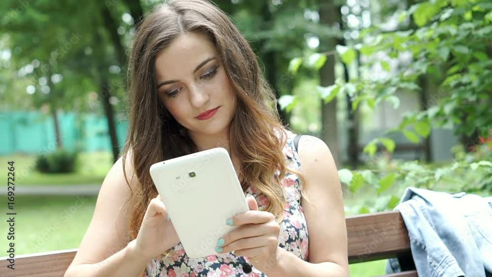 Pretty brunette in floral shirt browsing internet on tablet in the park, steadycam shot
Pretty brunette in floral shirt browsing internet on tablet in the park, steadycam shot